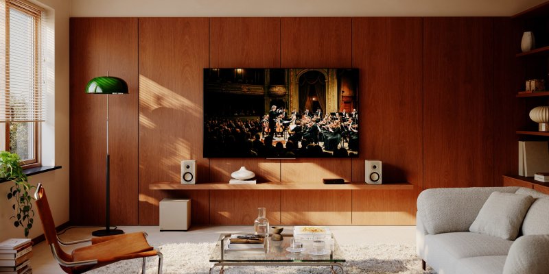 DALI BASIK SUB in Caramel White in a living room with bookshelf speakers