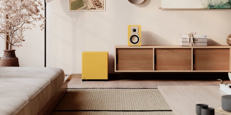 DALI BASIK SUB in Golden Yellow in a living room beside an oak sideboard
