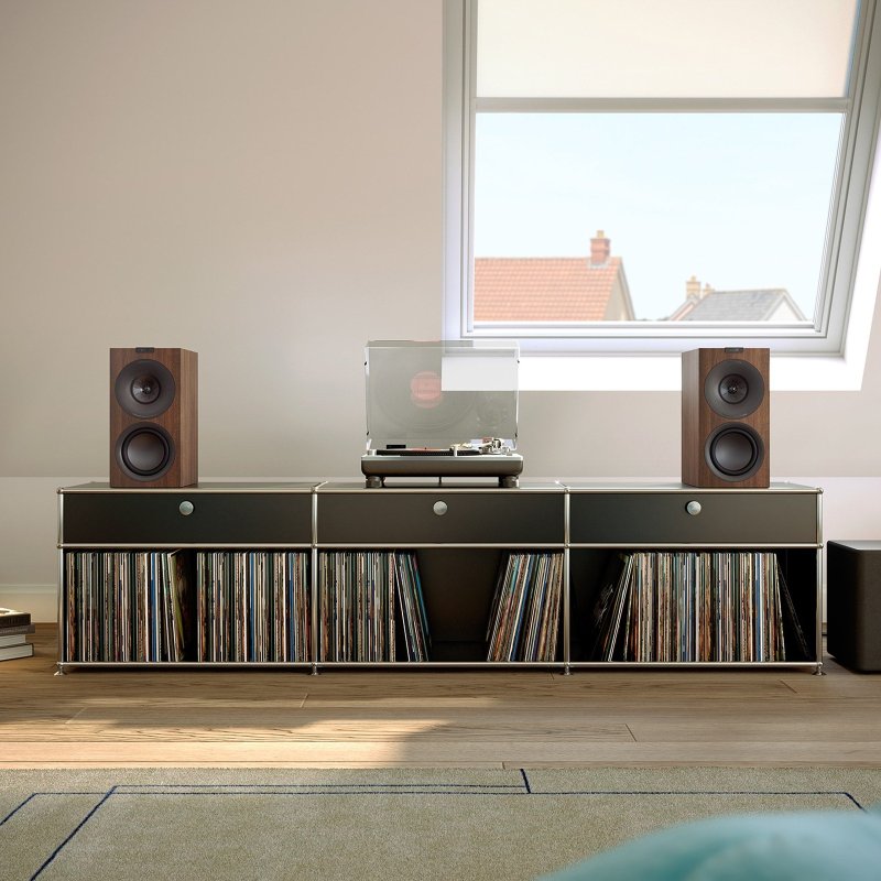 KEF Q Concerto Meta Standmount Speakers in a living room with a turntable and record storage, Walnut finish shown