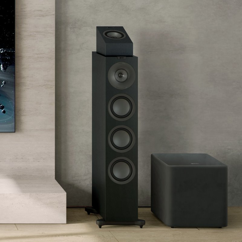 KEF Q8 Meta Dolby Atmos speaker in Satin Black placed on top of a KEF Q7 Meta floorstander in a living room (one unit shown)